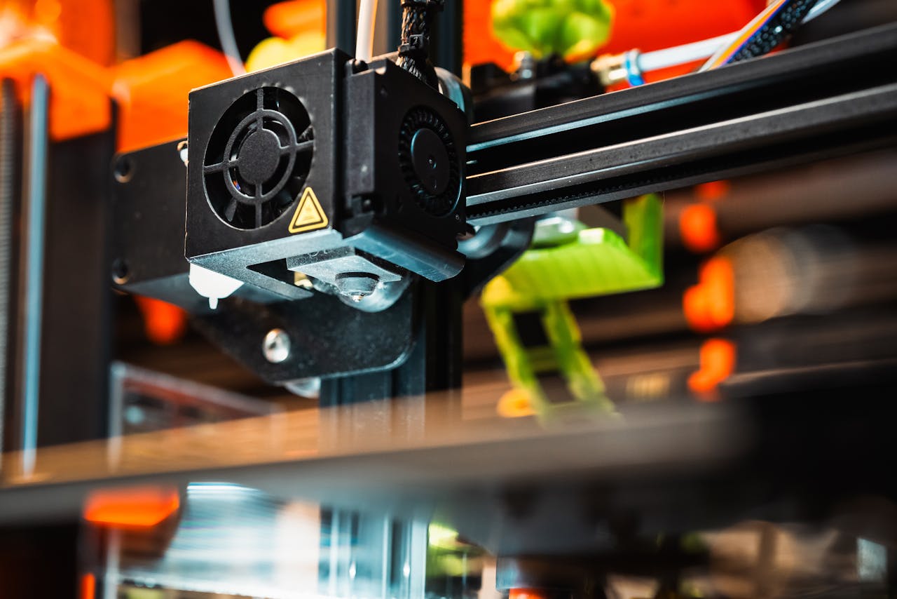 menu-01 Detailed view of a 3D printer nozzle working in a modern manufacturing setting.